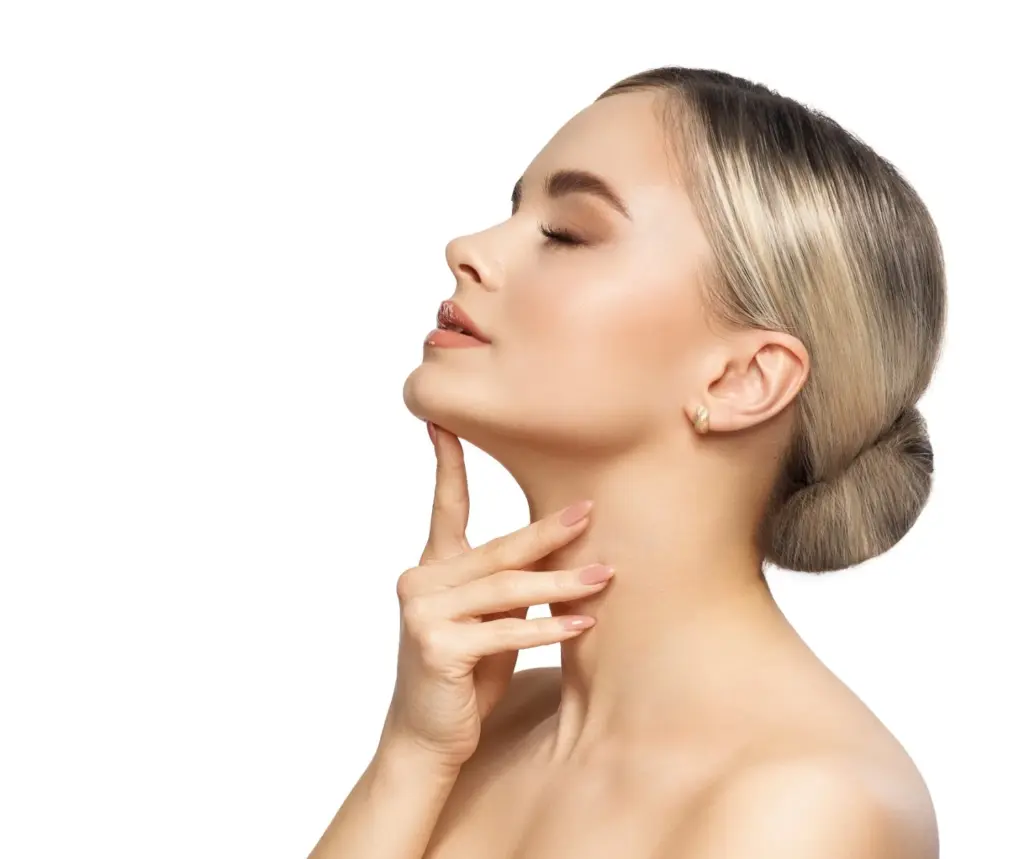 Side-profile portrait of a woman with smooth, clear skin and hair in a sleek bun, gently touching her chin against a clean, light background, suggesting skincare or aesthetic treatment results.